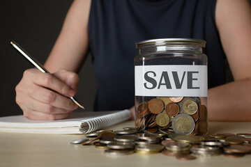 Woman is writing and note for amount of money and interest rate for saving. Saving money, investment, banking and finance concept. Plan for retirement.
