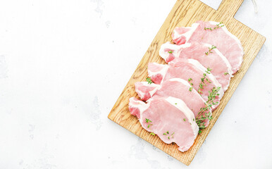 Raw pork chops, meat on cutting board prepared for cooking. White kitchen table,  top view