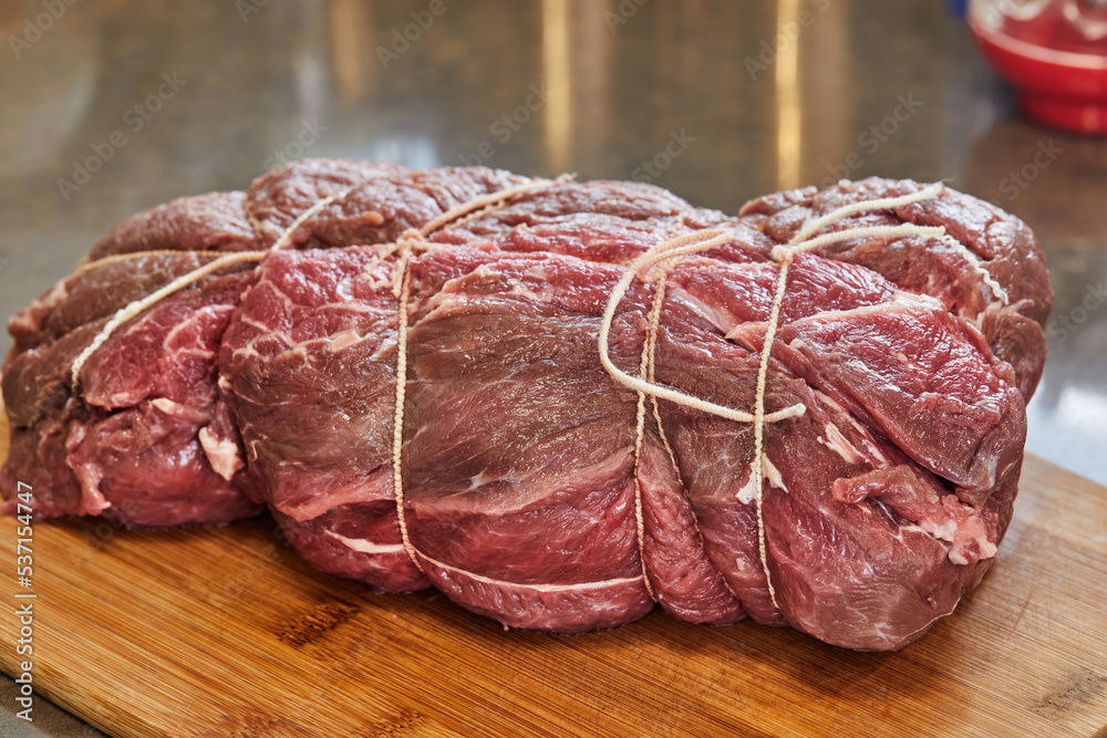 Canvas Prints Piece of beef tied with special food ropes on wooden cutting board in home kitchen