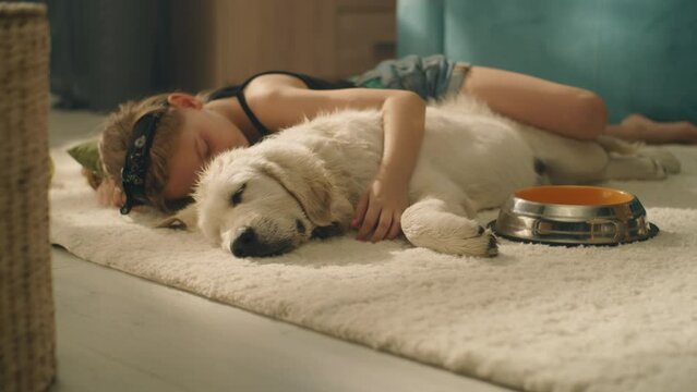 Girl hugging dog, daytime sleeping on mild carpet, watching dreams, spending leisure time at home together, relax and gathering strength. Golden retriever.