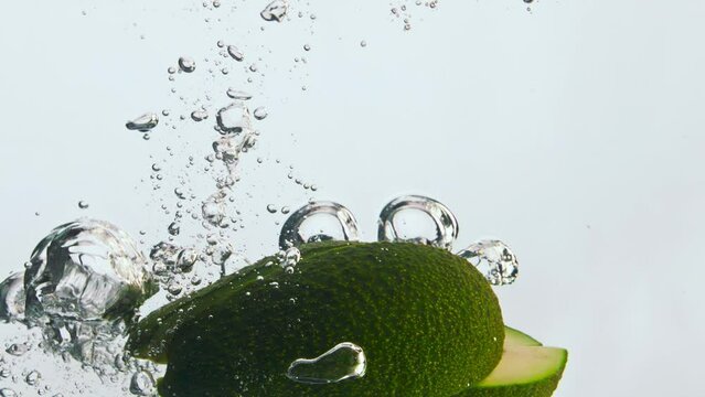 Avocado pieces splashing water in super slow motion close up. Organic tasty food