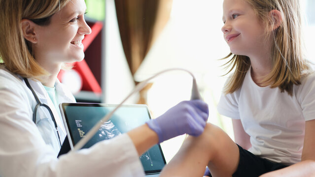Female doctor making ultrasound diagnostics of knee joint of child