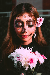 High quality photography. Woman with catrina makeup for day of the dead or halloween holding a bouquet of white flowers and red roses. Latin woman with skull makeup.