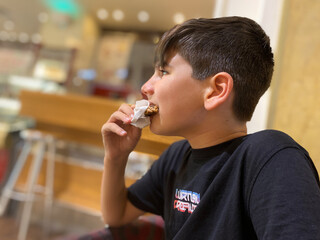 Boy eating a chocolate cookie with a napkin to avoid staining