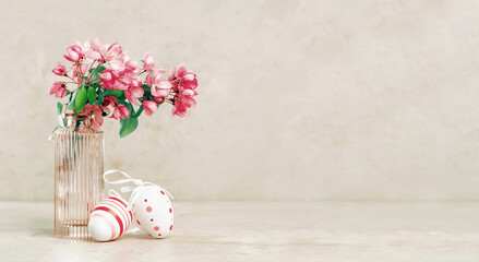 Happy Easter. Easter eggs on spring festive blooming with pink white flowers fruit tree branches in small vase against tender pastel background. Fresh floral background banner copy space