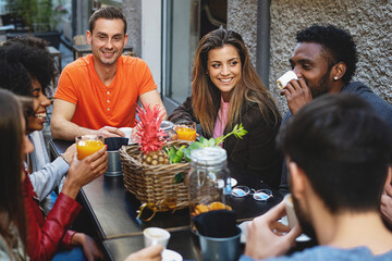 Group of young multiethnic young people at breakfast talking all together having fun at the brunch breakfast