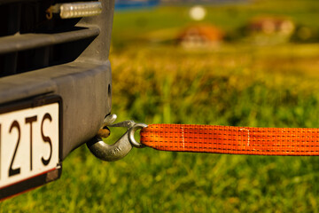 Tow hook with orange strap on car. Towing equipment.