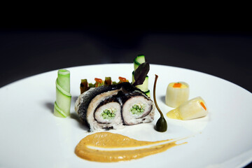 Fish fillet stuffed with cucumber. Rolled fish fillet in nori with vegetables on a black background. Asian seafood sushi. Side view