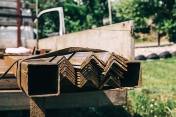 Steel profile tubes, corners and rods for the concrete reinforcing lies in the truck. Reinforcement bars delivery to the construction site. Strong metal building element. Rebar close-up. Copy space