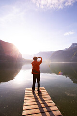 Verticel  of Back view young tourist man in  packpack using smartphone take picture at Hallstatt mountain village lake in the Austrian Alps