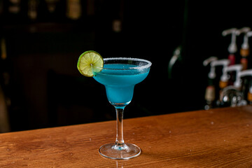 Blue margarita exotic alcoholic cocktail with tequila, liqueur, lime juice, salt and ice, summer blue background, place for text
