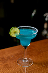 Blue margarita exotic alcoholic cocktail with tequila, liqueur, lime juice, salt and ice, summer blue background, place for text