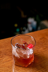 Old-fashioned drink at bar with a slice of orange, cherry and ice, a classic alcoholic drink