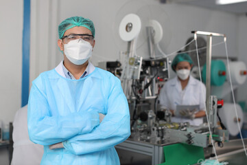 Fototapeta na wymiar Worker in personal protective equipment or PPE inspection quality crossed arms and looking camera in mask and medical face mask production line factory, manufacturing industry and factory concept.