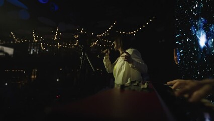 woman is singing slow song in gig, rock or pop ballad, keyboardist is playing music