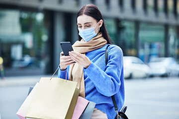 Woman, shopping in covid mask with smartphone, communication about sale or discount at retail mall. Young shopper in pandemic, bags and contact car service for travel and buyer with urban background.