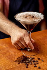 Fototapeta na wymiar delicioso martini espresso en un vaso junto a granos de café sobre una mesa de madera