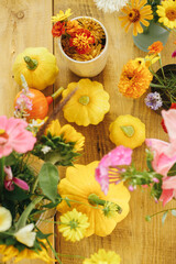 Obraz na płótnie Canvas Autumn composition on rustic table. Colorful autumn flowers in vase, pumpkins and pattypan squashes on rustic wooden table. Harvest time in countryside. Hello Fall
