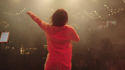 concert of young singer woman, rear view of female figure, view from stage to audience hall