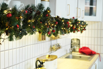 Interior white kitchen with christmas decor and decorated fir tree.