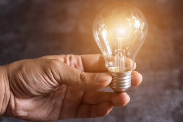 Hand of man holding illuminated light bulb, idea, concept creativity with bulbs that shine glitter.
