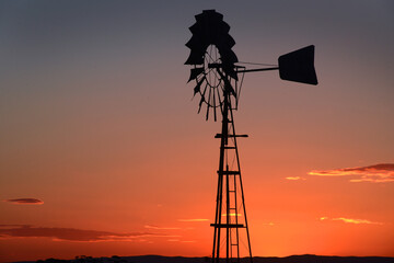 A warm Australian sunset silhouettes the irrigation pump in the paddock against the rich sky