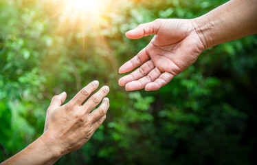 Hand helping hand, reaching, giving a helping hand, hope and support each other over blur bokeh nature background, Concept of develop a friendship and international day of peace.