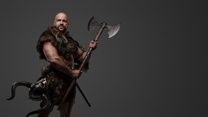 Shot of muscular antique viking with huge axe dressed in armor and fur.