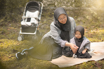 Fototapeta premium Happy family of mother and daughter in hijab in nature park in summer. southeast asian family