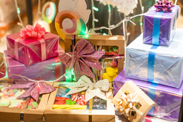Fototapeta na wymiar Stylish christmas gift boxes with ribbons and bows in window store in evening. Christmas festive street decor, holiday winter shopping and sales. Merry Christmas.