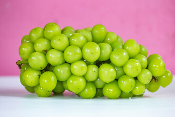 Shine Muscat grapes on white table and pink background