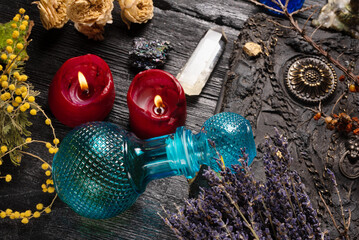 Old magic book and dry natural herbs and remedy bottle on the wooden table close up background.