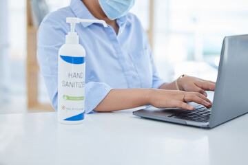 Covid, hand sanitizer and a woman in office typing on laptop with face mask. Online work, hygiene...
