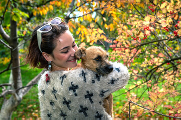 Smiling woman with dog in autumn park. Portrait of happy young woman with dog outdoors in autumn