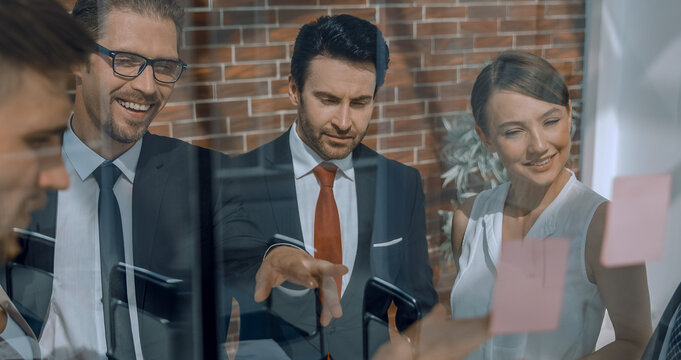 business team showing on the notes on the glass Board