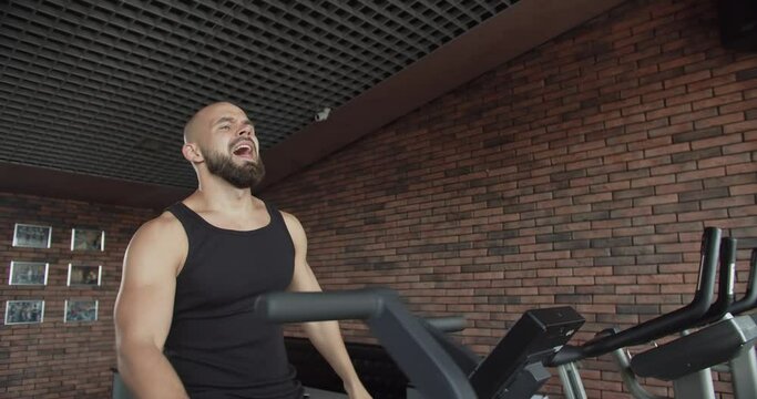 A young man does sports on the orbitrek simulator in the gym