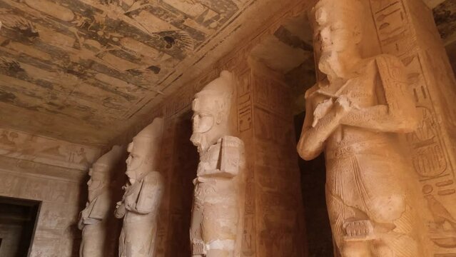 Looking Up At Sculpted Statues Inside The Great Temple Of Ramses II At Abu Simbel With Birds Flying Past