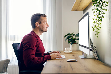 A man following an online course from his home office and typing assignment.