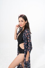 Studio portrait photo of a young beautiful elegant Brazilian female model lady wearing black color swimsuit bikini, sunglasses and beach scarf posing with a series moments of emotion and gesture 