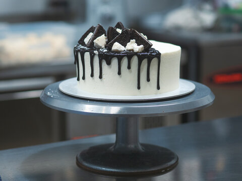 Chef Decorating White Icing Drip Cup Cake With Oreo Cookies And Dark Chocolate