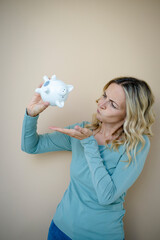 Fototapeta na wymiar pretty young woman with white piggy bank in front of brown background