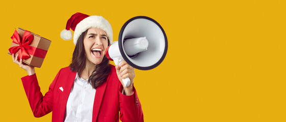 Excited noisy woman in santa hat shouting into loudspeaker announcing winter discounts. Woman in...