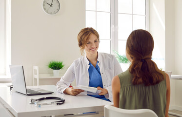 Friendly doctor talking to her young patient. Happy, smiling woman who works as a general...