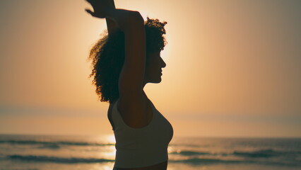 Fototapeta premium Sporty girl warming body in front sunrise close up. Silhouette athletic woman.