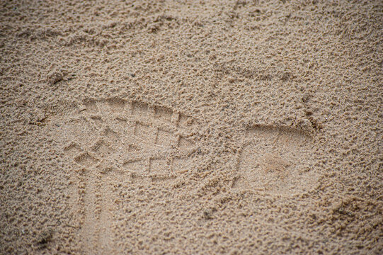 Small child bare foot print on a warm sand and adult shoe print. Summer holiday and time concept. Copy space. Day on a beach. Parents looking after small one theme