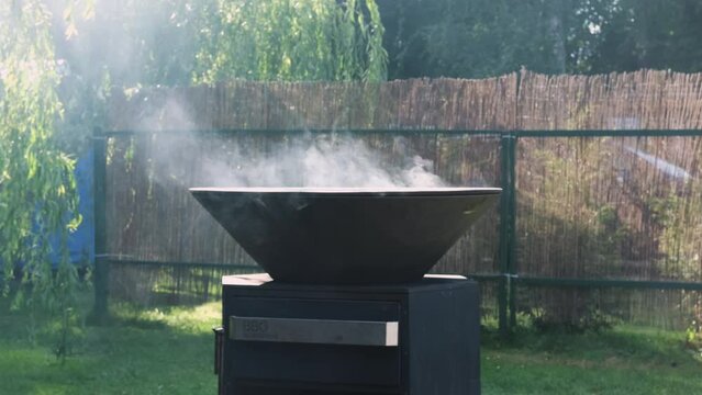 Round black modern grill . Round table-cooking surface. Steam comes out of the grill. Slow motion video