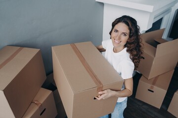 Friendly girl holding donation box prepares things for charity. Charitable activity, relocation