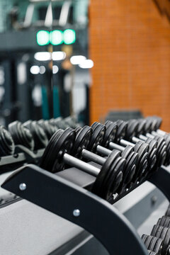 Close up set of dumbbells on black metal steel on rack in sports fitness center.