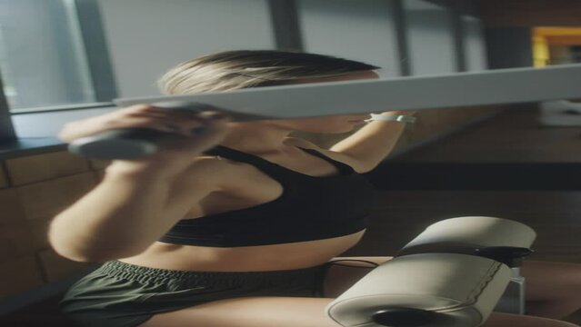 Vertical shot of athletic woman using lat pulldown machine while exercising in gym