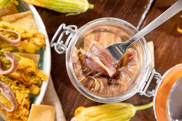 Anchovies in a jar, on a wooden rustic background. Traditional italian food of the south of italy and sardinia. Anchovy Fillets. small but herring. 
